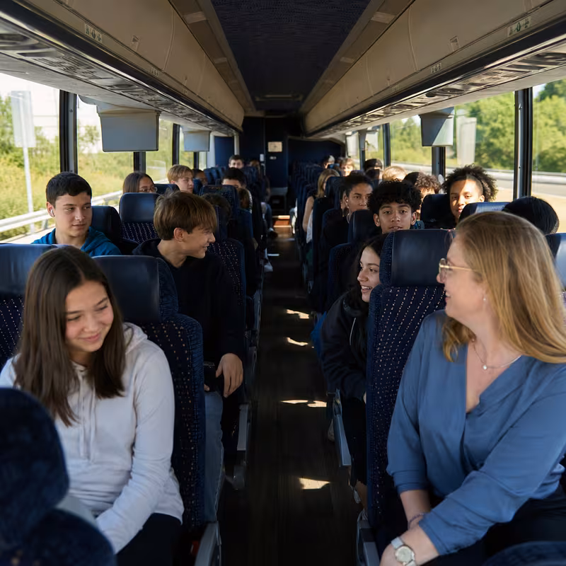 Group boarding a white charter bus for School Transportation transportation in Arlington